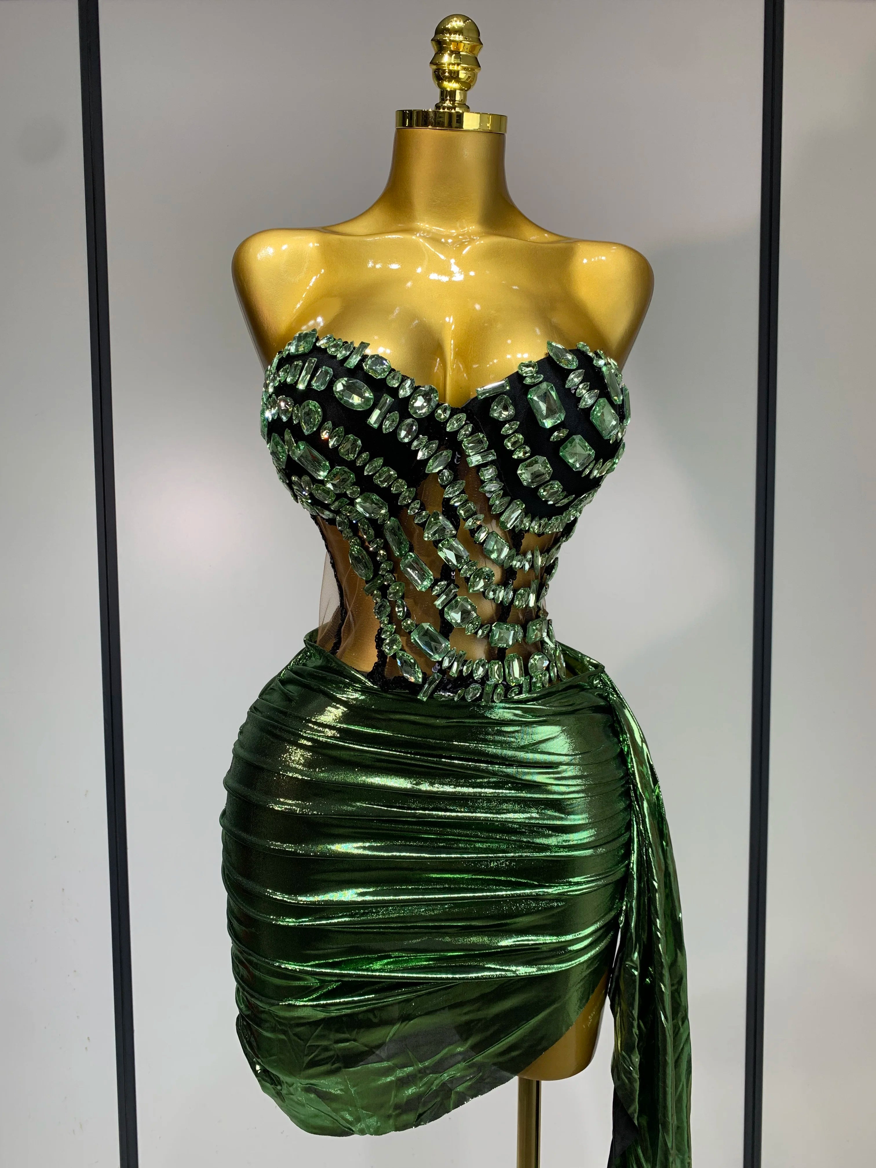 Green beaded dress on a mannequin against a neutral background