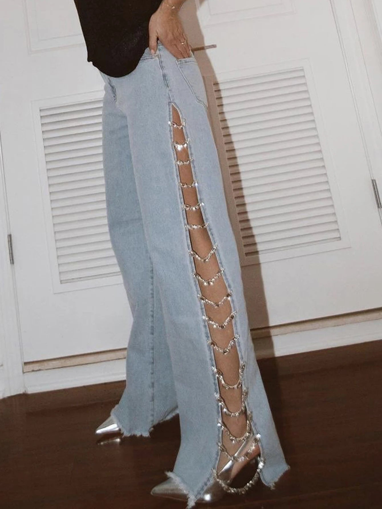 Light blue jeans with decorative cut-out side panels worn by a person indoors.