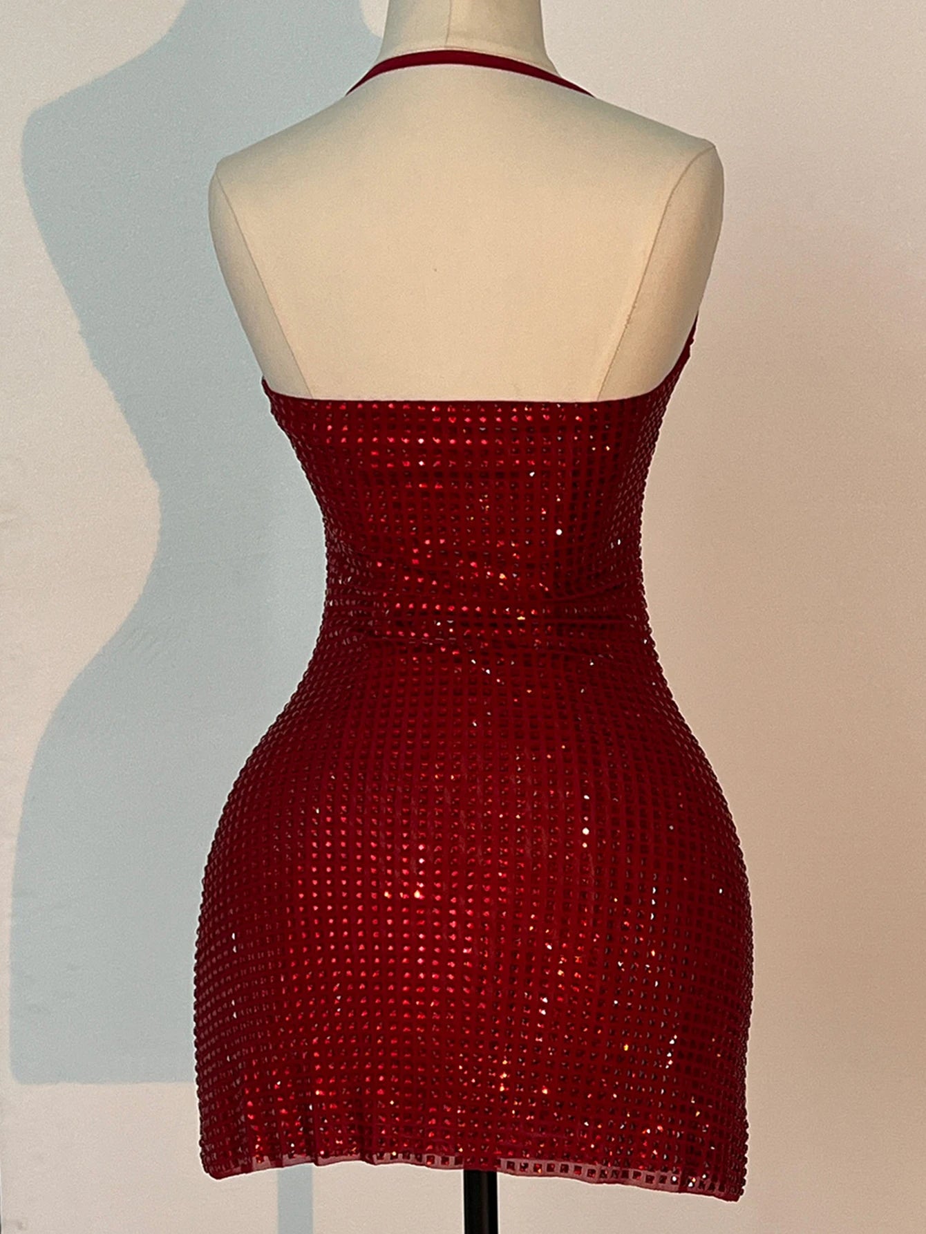 Red beaded dress on a mannequin against a plain background
