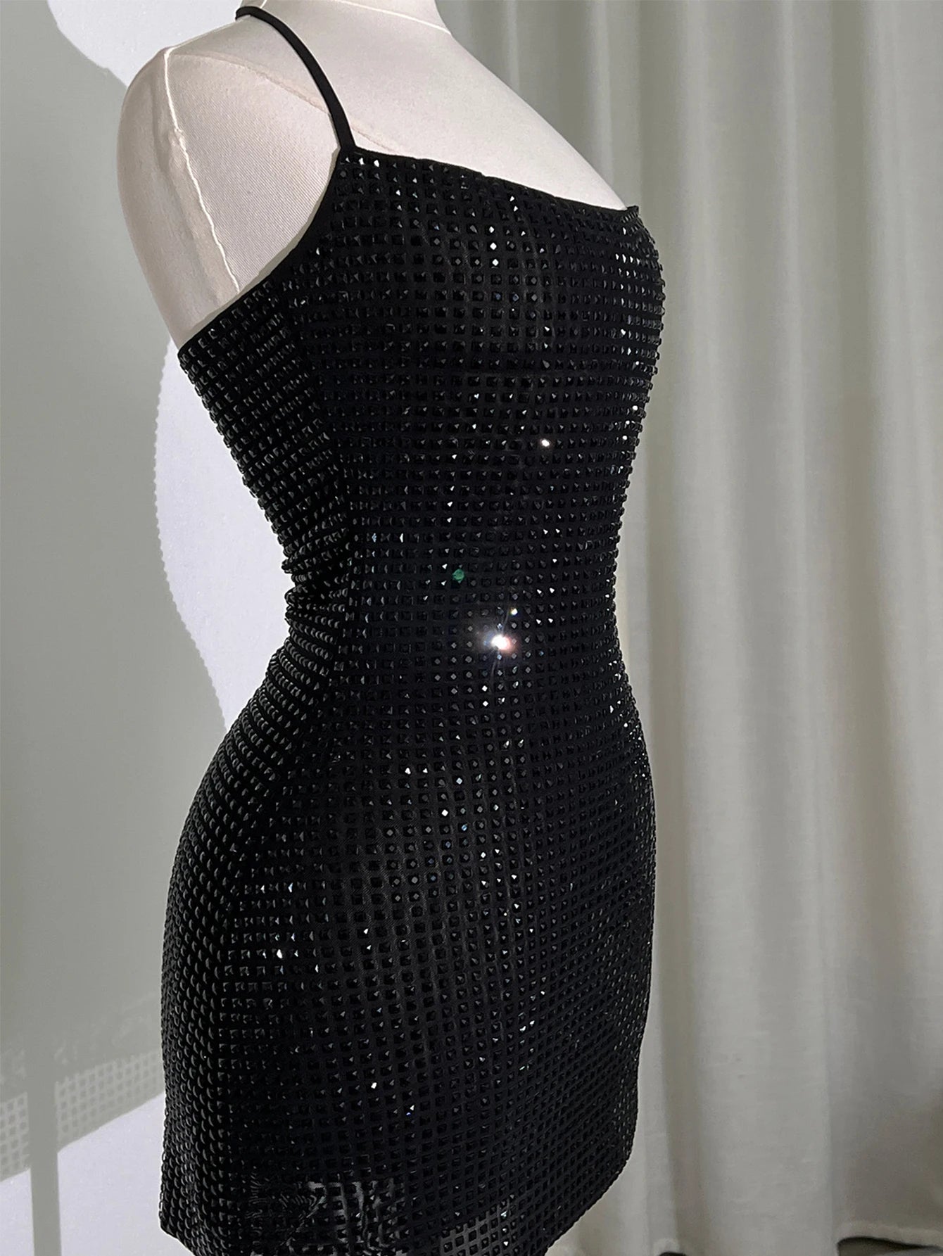 Black sequin dress on a mannequin against a neutral background