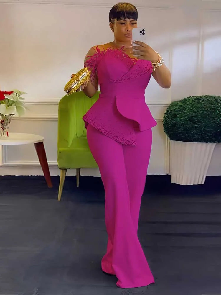 Person wearing a bright pink outfit with a matching top and pants, standing in a room with a green chair and decorative items.