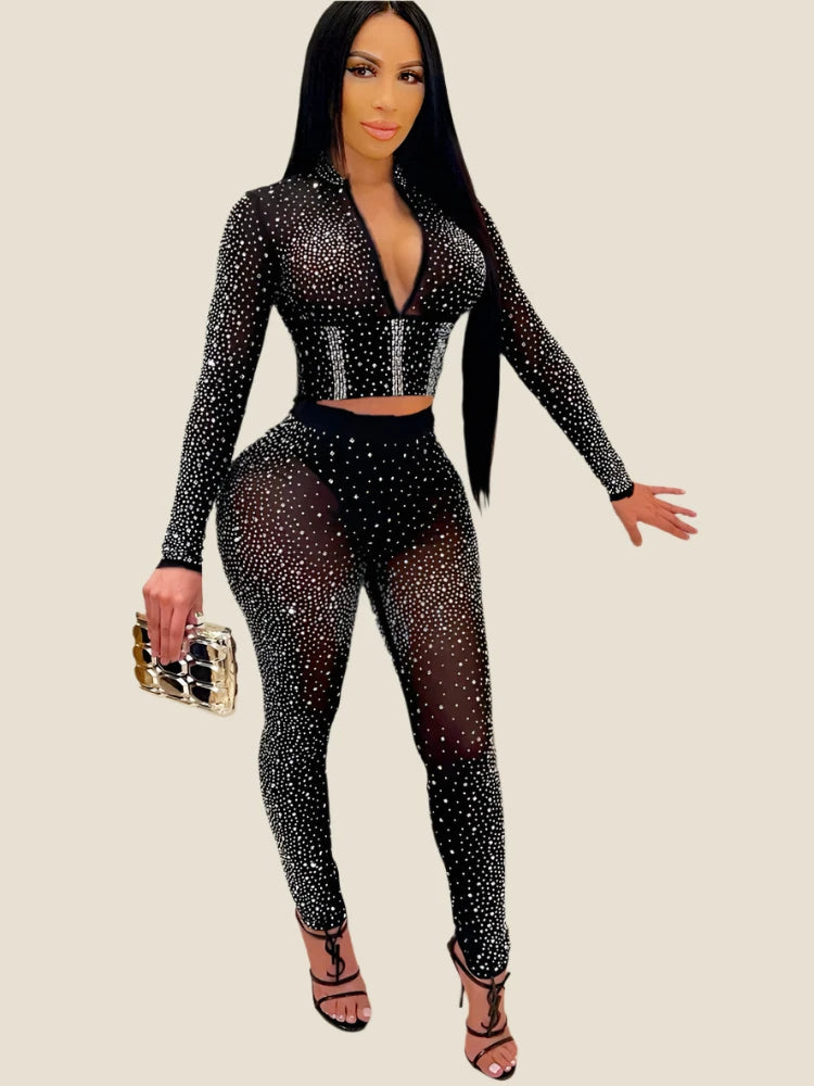 A woman wearing a crystal-studded black crop top and matching high-waisted pencil leggings, with a stand collar and full sleeves.
