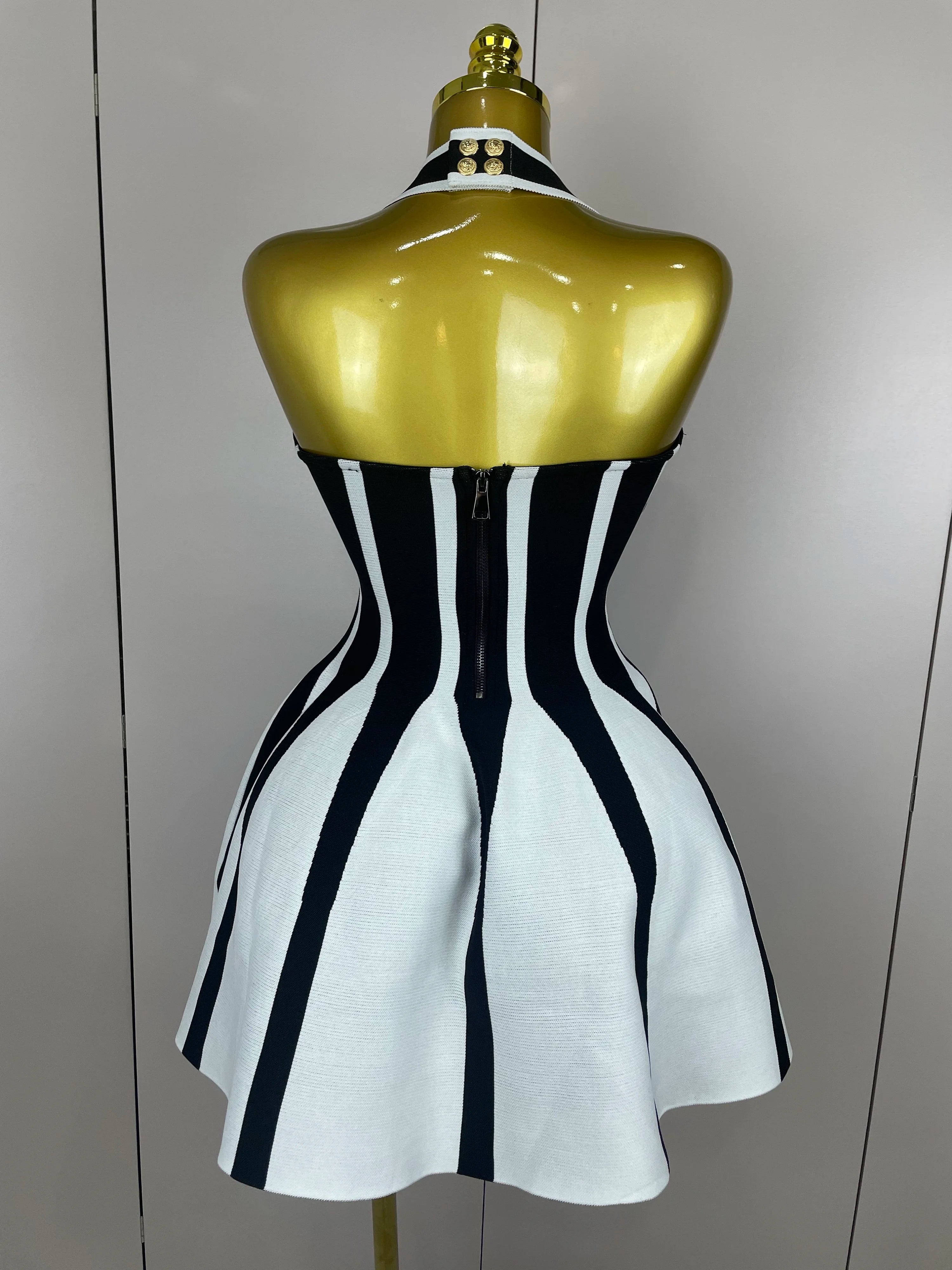 Mannequin wearing a black and white striped dress with a gold top against a plain background