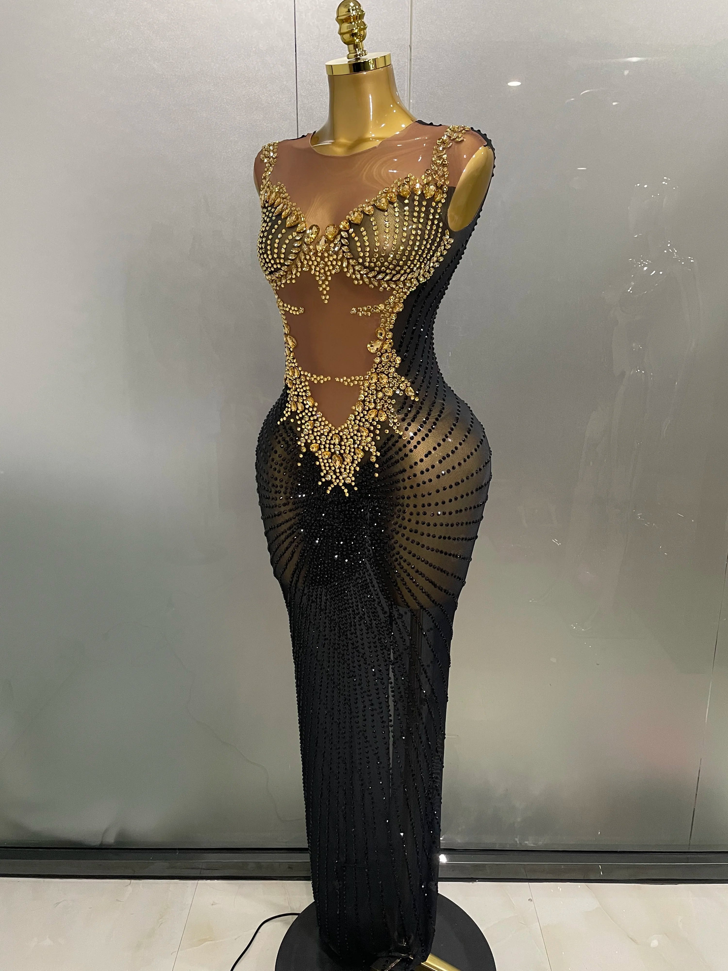 Mannequin wearing a black evening gown with gold embellishments against a plain background