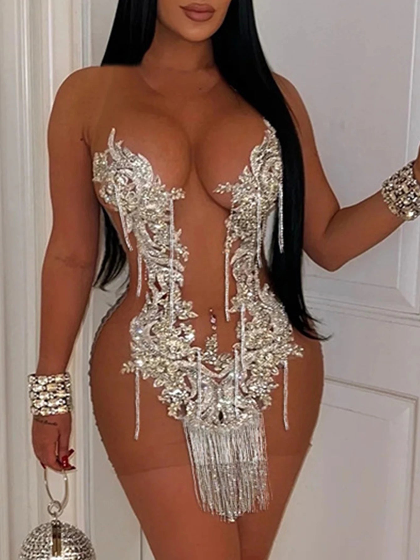 Person wearing a sparkling silver bodysuit with intricate designs and tassels.
