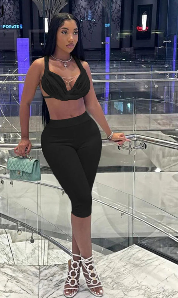 Woman in a black outfit holding a green handbag in an indoor setting