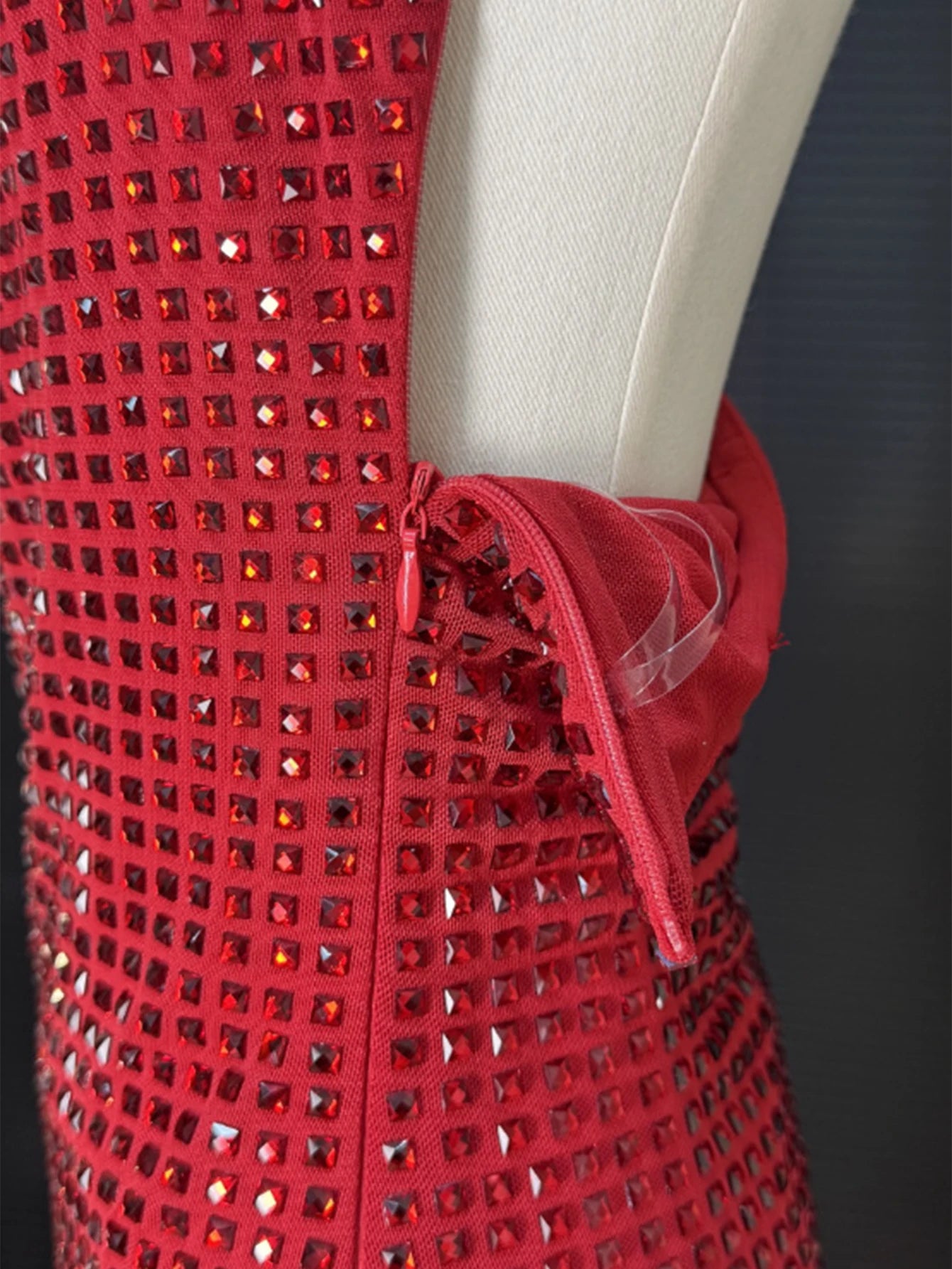Red dress with rhinestone embellishments on a mannequin against a dark background