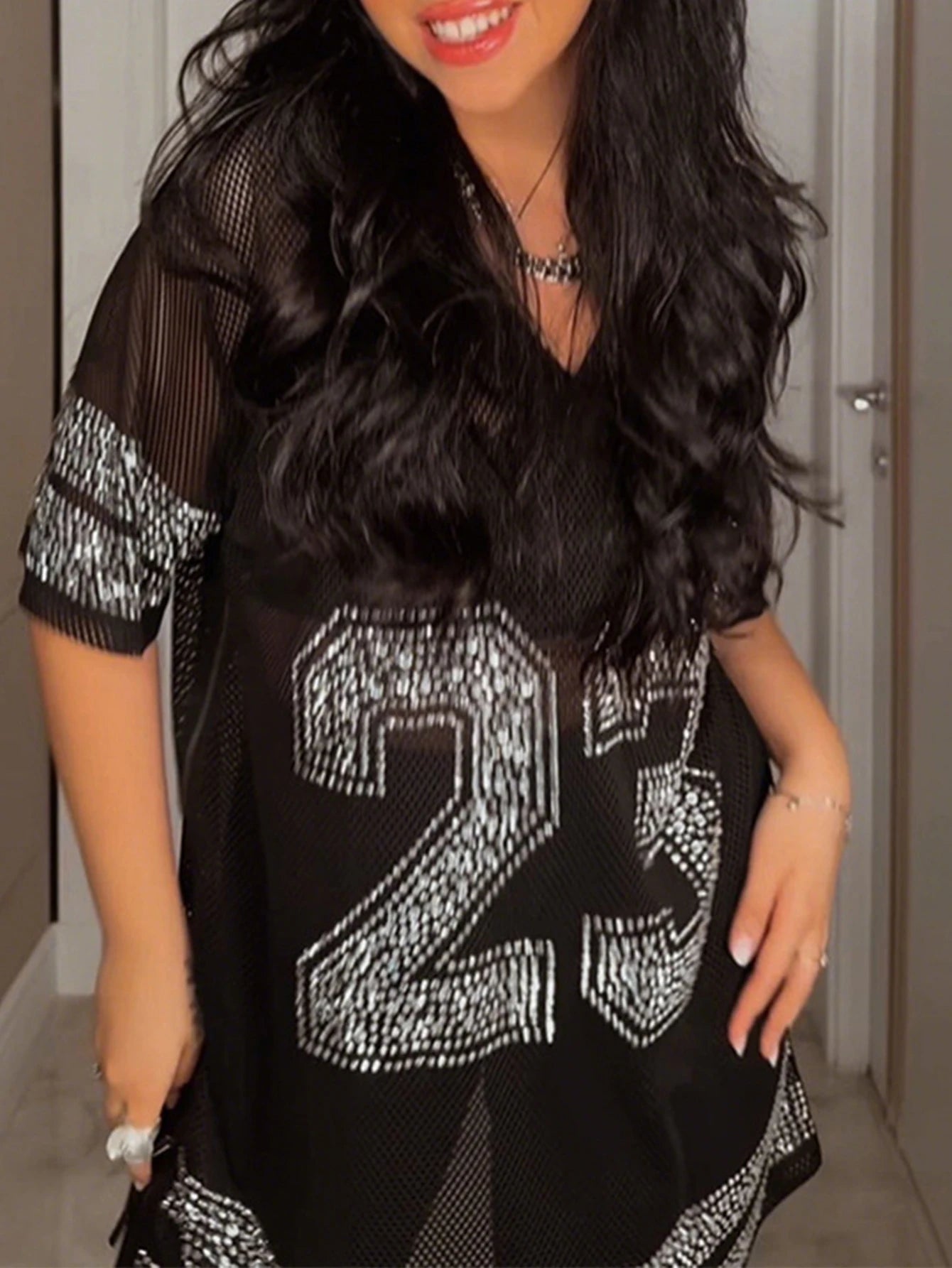 Person wearing a black outfit with large white numbers, standing indoors.