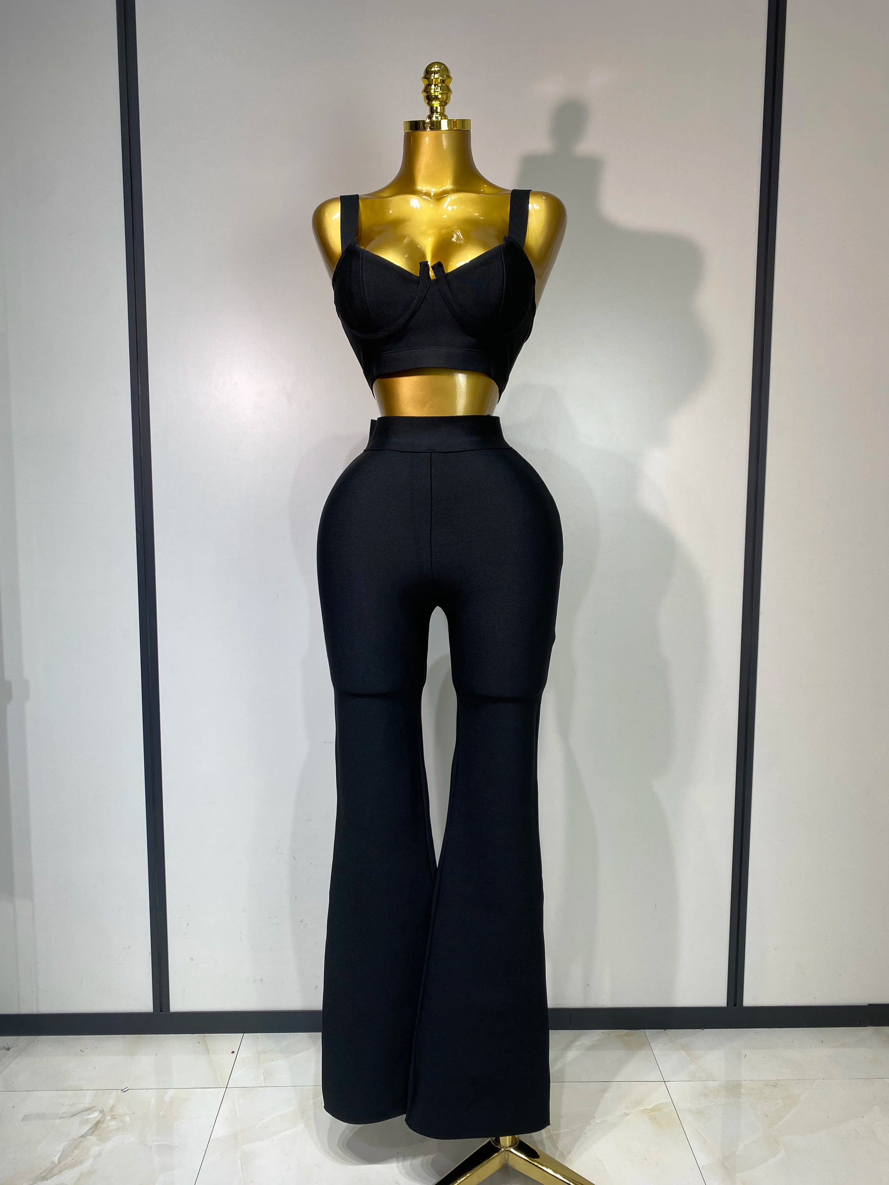 Mannequin wearing a black outfit with a high-waisted top and flared pants on a white background