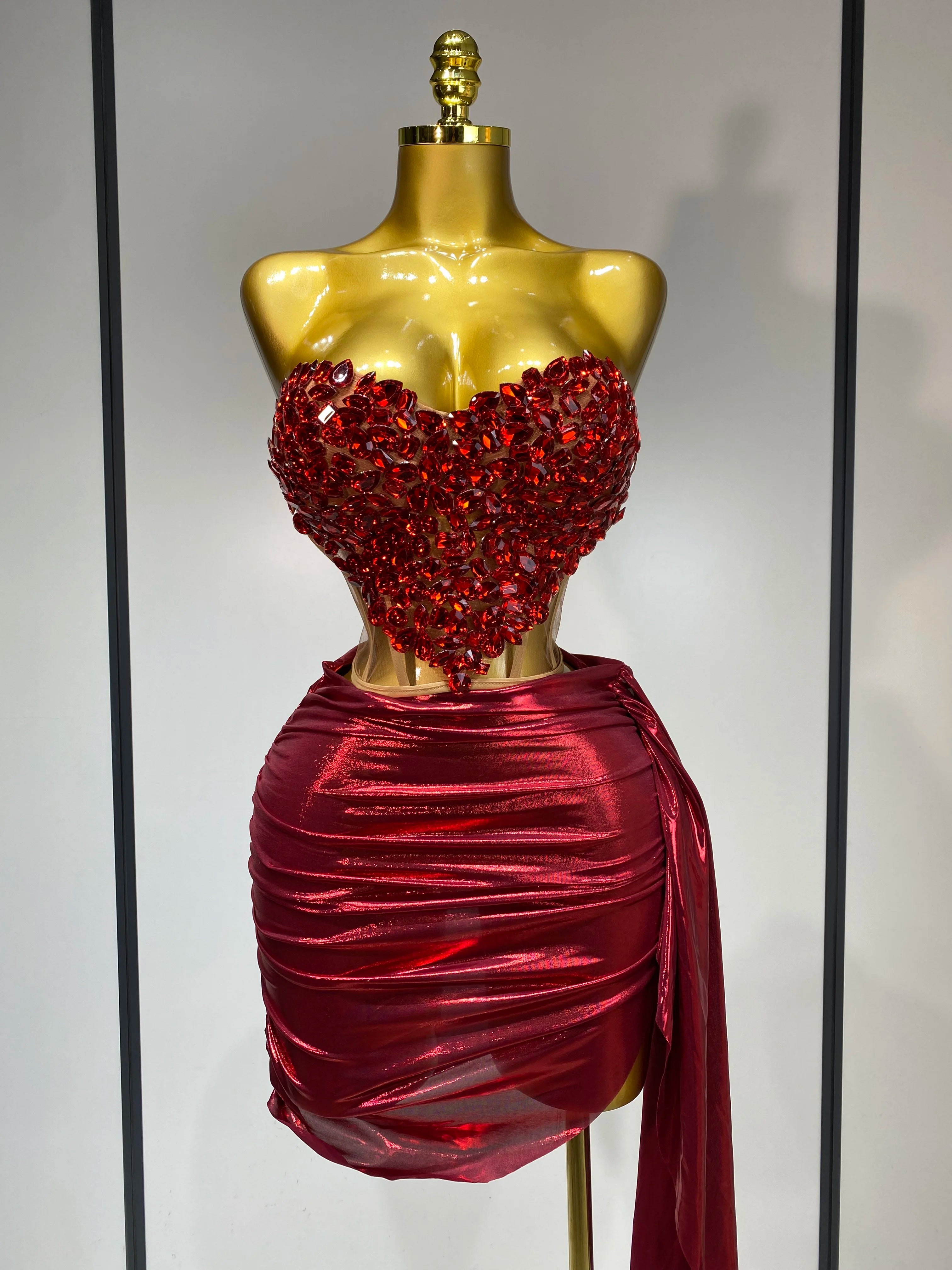 Mannequin wearing a red beaded top and skirt against a neutral background